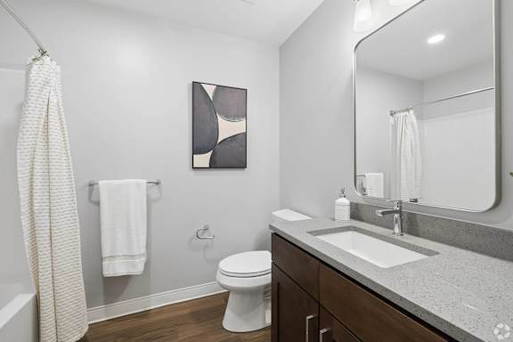 A bathroom with a toilet, sink, and a mirror.