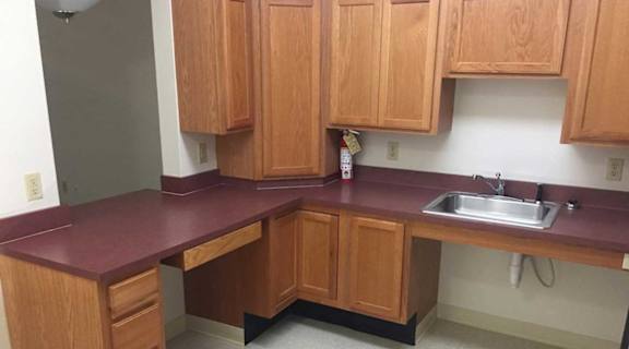 A kitchen with wooden cabinets and a maroon countertop.