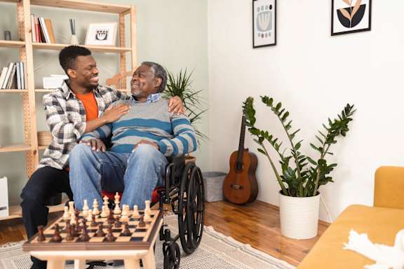 A man in a wheelchair playing chess with another man.