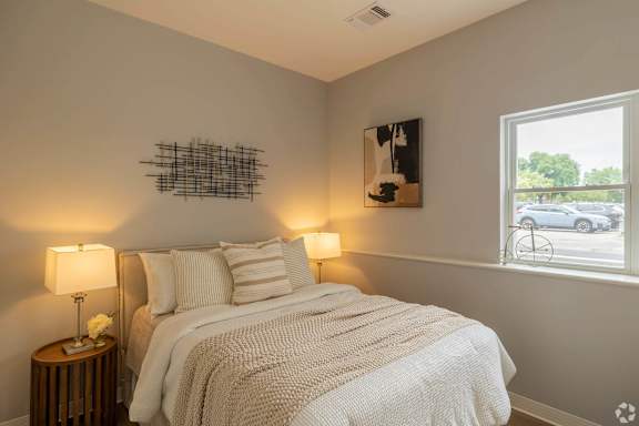 A bedroom with a bed, two lamps, and a picture on the wall.