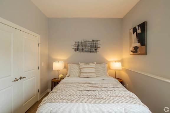A bedroom with a large bed and two lamps on either side.