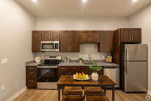 A kitchen with a table and chairs in front of a refrigerator.