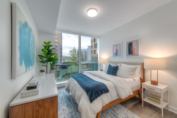 a bedroom with a large window and a bed with a blue blanket