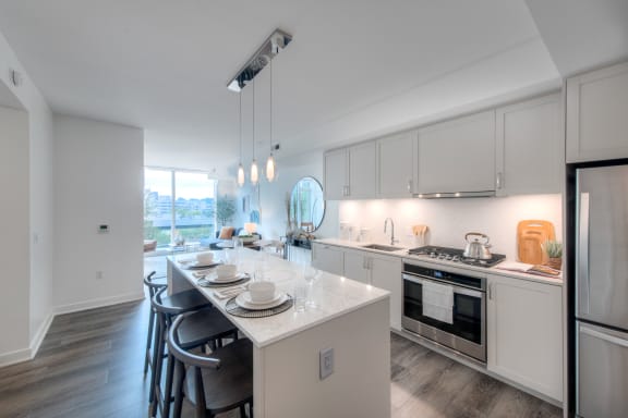 an open kitchen with white cabinets and a marble counter top