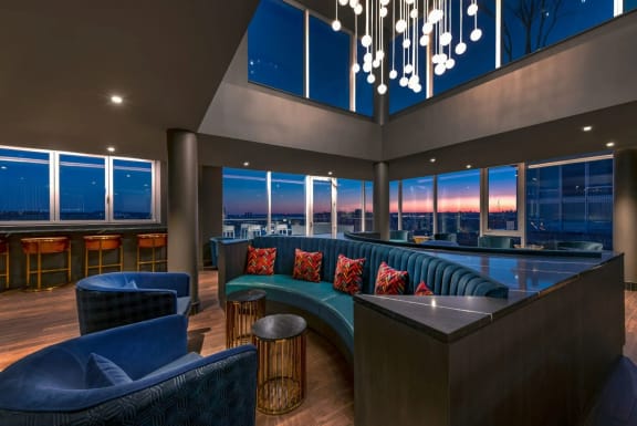 a lounge area with blue furniture and a view of the city at night