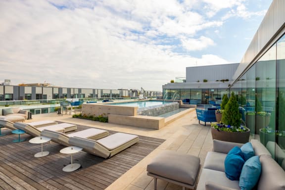a rendering of a rooftop deck with couches and tables and a pool