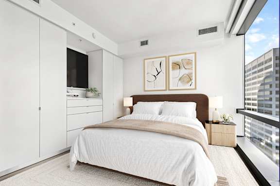 A modern bedroom with a large bed and a balcony overlooking the city.