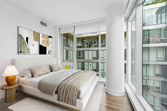 A bedroom with a large bed and a lamp on a side table.