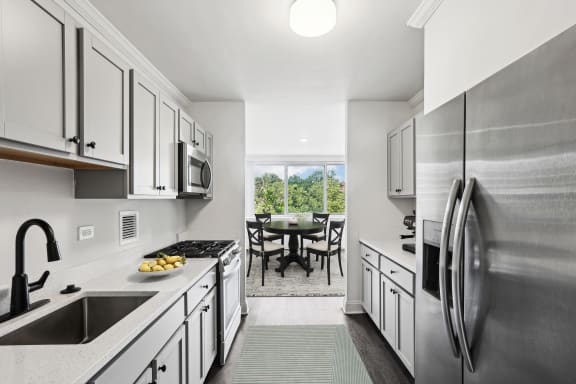 a living room with a white couch and a kitchen with stainless steel appliances