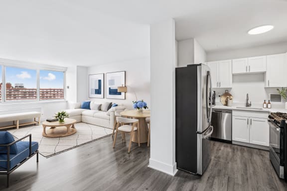 a living room with a white couch and a kitchen with stainless steel appliances