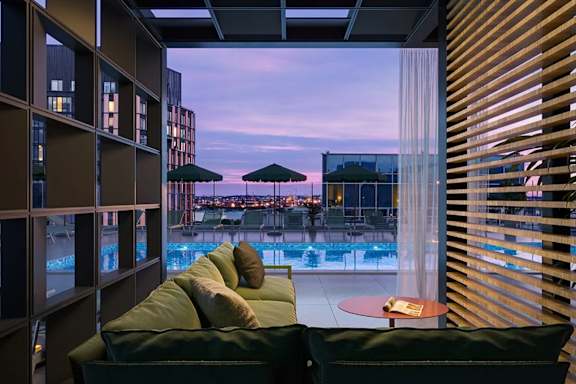 A modern living room with a view of the city at dusk.