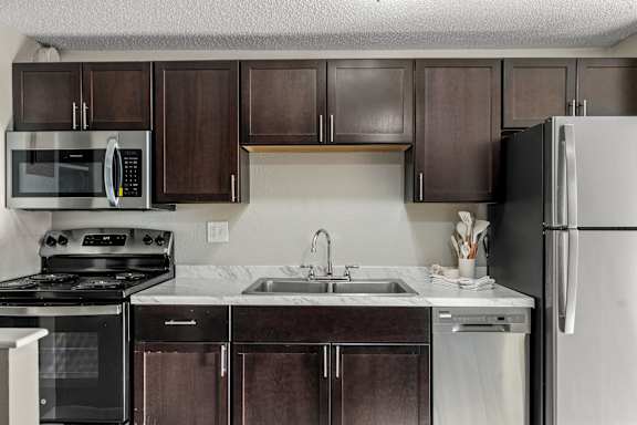 A kitchen with dark brown cabinets and a white fridge.