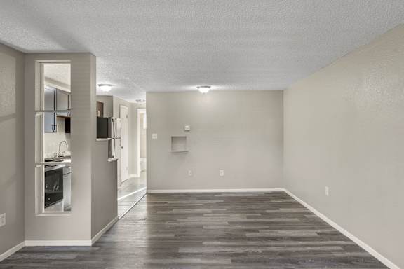 A spacious room with a kitchen area to the left and a hallway leading to another room.
