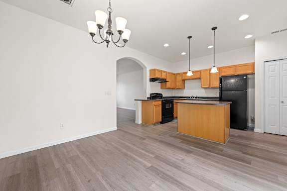 A kitchen with a black refrigerator and wooden cabinets.