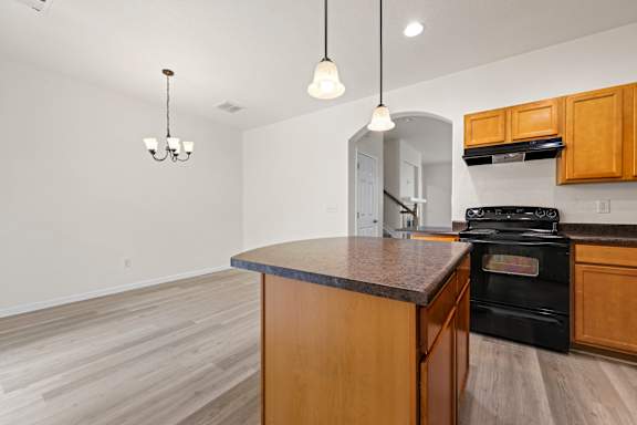 A kitchen with a black stove top oven and wooden cabinets.
