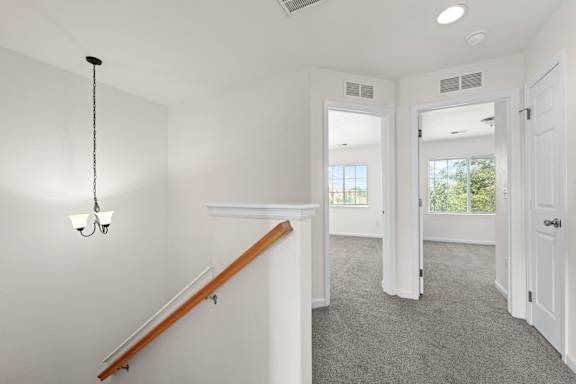 A white room with a staircase and a chandelier.