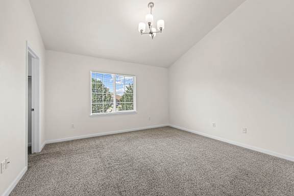 A room with a carpeted floor and a window showing trees outside.