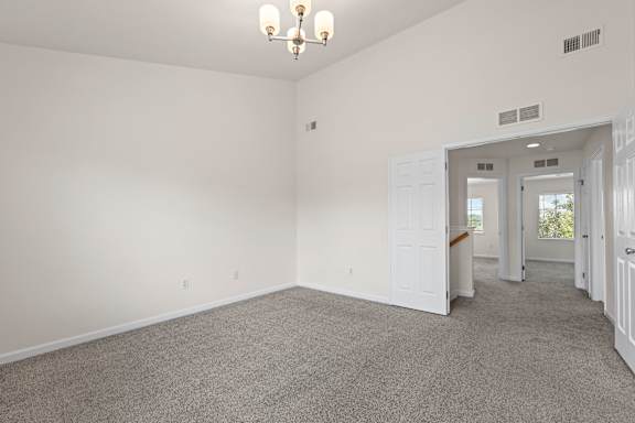 A spacious room with a carpeted floor and a chandelier hanging from the ceiling.