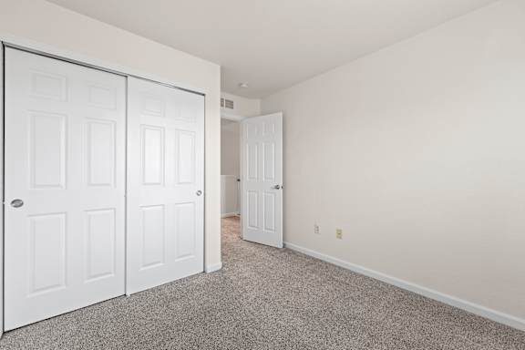 A room with white doors and carpeted floor.