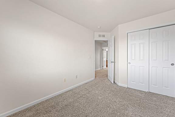 A spacious room with white walls and carpeted floor.