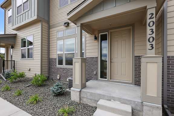 A modern house with a beige front door and a number 20303 on the wall.