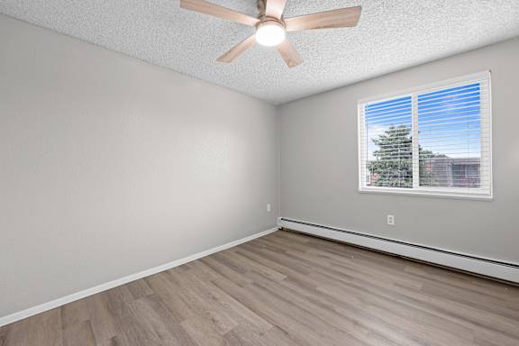 A room with a ceiling fan and a window with blinds.