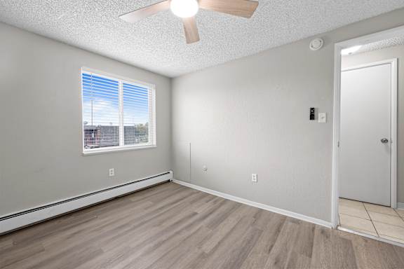 A room with a ceiling fan and a window with blinds.