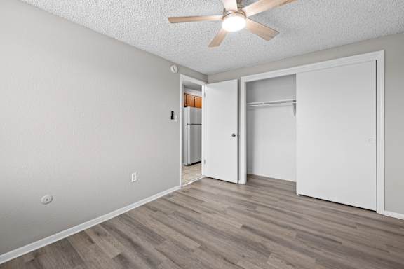 A room with a ceiling fan and a door leading to another room.