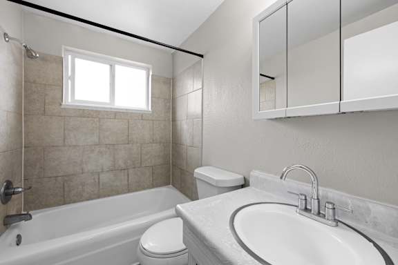 A white bathroom with a tub, toilet, and sink.