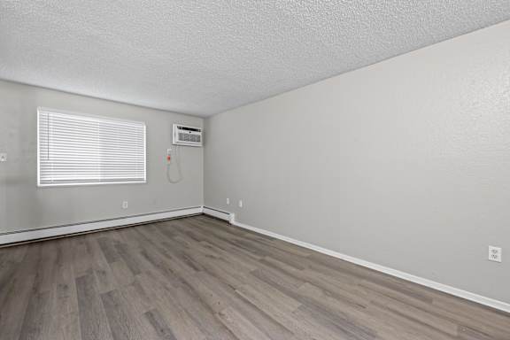 A room with a window and a wood floor.