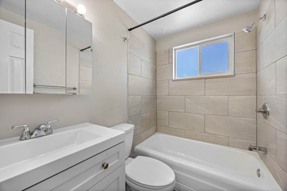 A white bathroom with a toilet, sink, and bathtub.