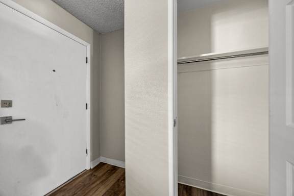 A white door is open to a room with a white wall and a white closet.
