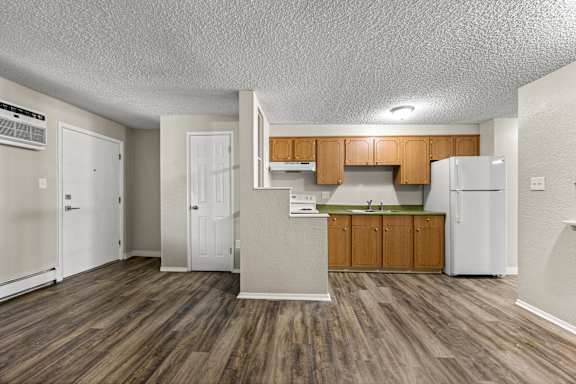 A kitchen with wooden floors and white appliances.