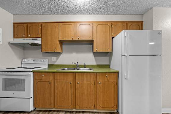 A kitchen with wooden cabinets and a white refrigerator.