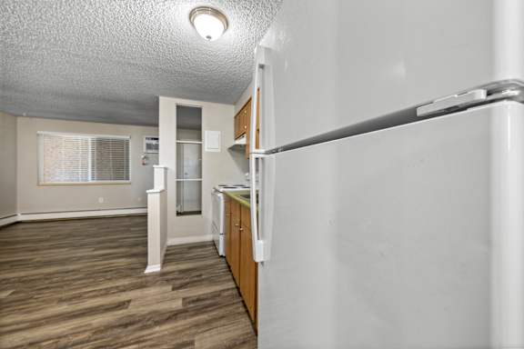 A kitchen with a white wall and wooden floors.