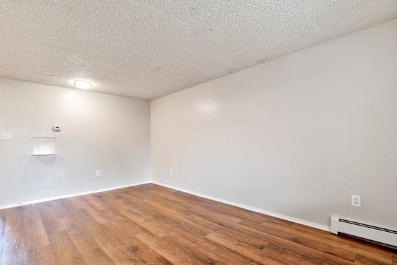 Empty room with brown flooring at Kingsbrook Arms, Englewood Colorado