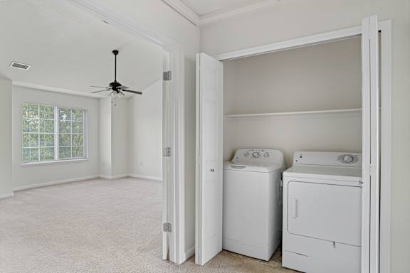 A room with a ceiling fan and two washing machines.