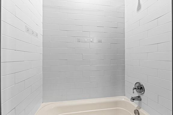 White bathroom with a tub and white tiled walls at The Point at Biscay, Aurora, CO, 80013