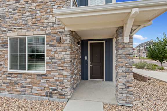 Front door of a brick house with a sidewalk and a window at The Point at Biscay, Colorado, 80013