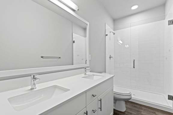Bright bathroom with two sinks and a toilet and a shower at The Point at Biscay, Aurora, CO