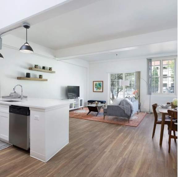 A modern kitchen with a white dishwasher and wooden floors.
