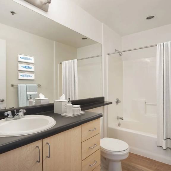A white toilet sits in a bathroom next to a sink and a bathtub.