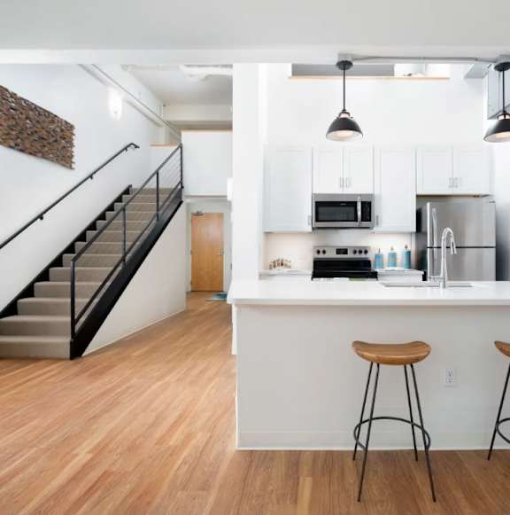 A kitchen with white cabinets and a bar area with stools.