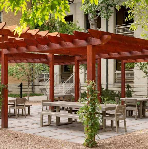 A wooden pergola with benches and a table underneath it.