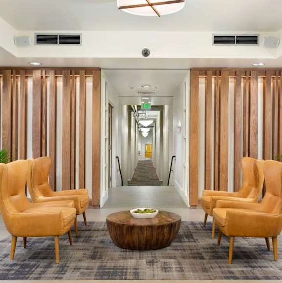 A hallway with orange chairs and a wooden coffee table.