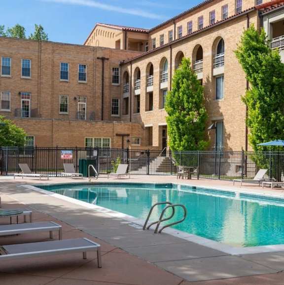 A pool area with a black fence and a building in the background.