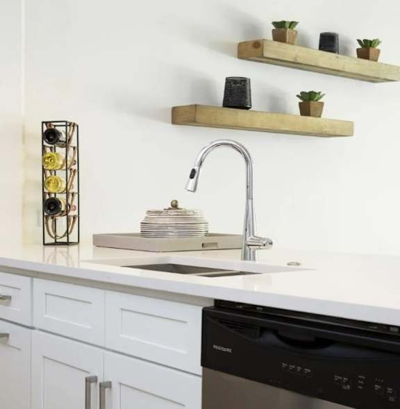 A kitchen with a black dishwasher and a sink with a silver faucet.