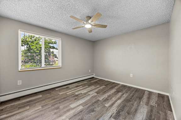 A room with a ceiling fan and wooden flooring.