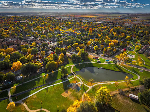 A beautiful aerial view of a park with a pond and a winding road.