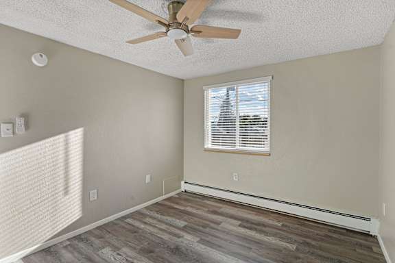 A room with a ceiling fan and a window with blinds.